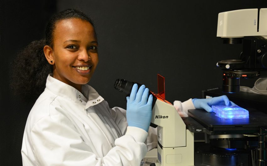 Ruth Bekele sitting at microscope